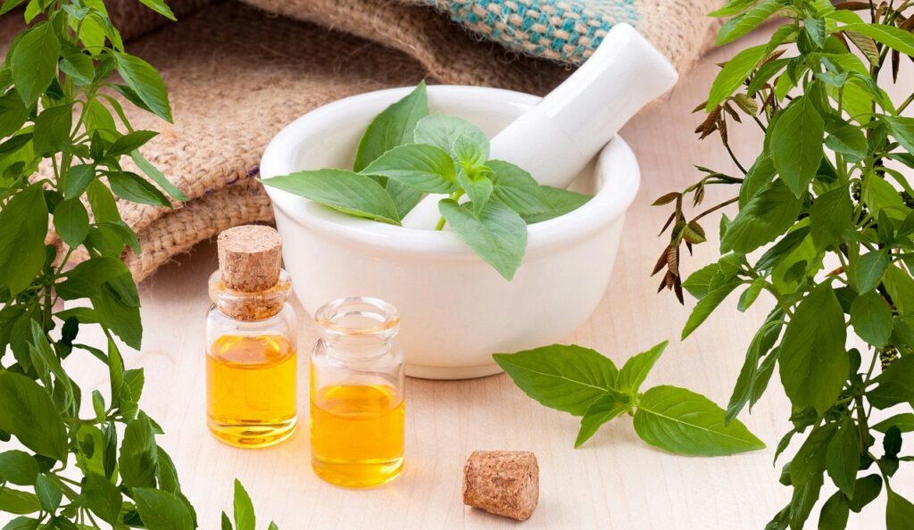 Essential oils with fresh herbs in a mortar and pestle, natural aromatherapy setup for relaxation